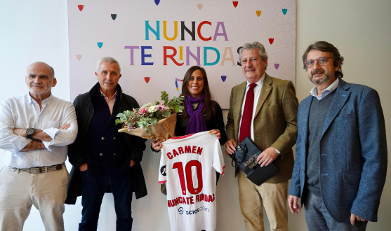 Foto de familia en la sede de la AECC con el mural de 'Nunca te rindas'.