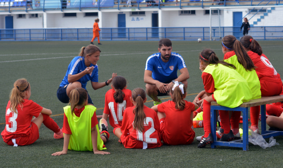 Dayi Borrego, entrenadora del equipo alevín femenino del Sevilla FC, da instrucciones durante un partido junto a Manuel Ferrusola