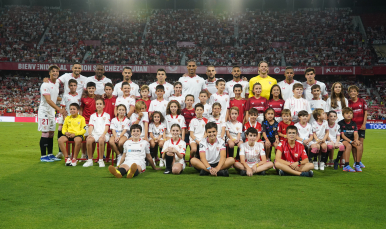 Los jugadores del primer equipo rodeado de niños antes de un partido.