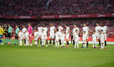 Los jugadores del Sevilla FC, junto a niños a la salida al césped.