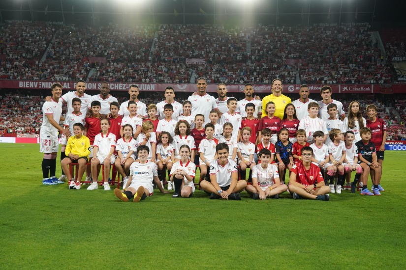 Los jugadores del primer equipo rodeado de niños antes de un partido.