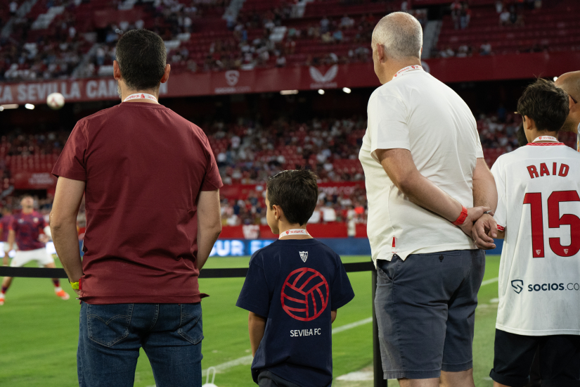 Aficionados ven el calentamiento a pie de césped.