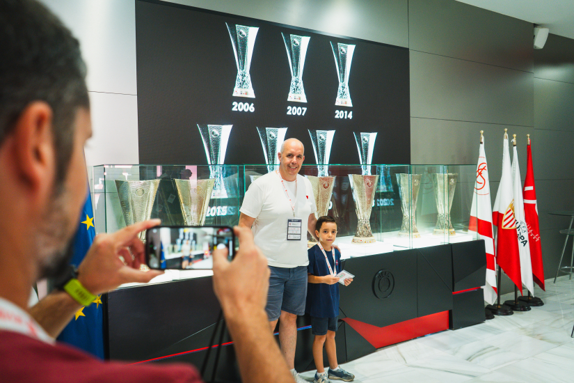 Unos visitantes se fotografían junto a las siete copas de la Europa League.