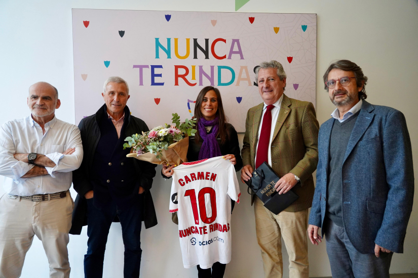 Foto de familia en la sede de la AECC con el mural de 'Nunca te rindas'.